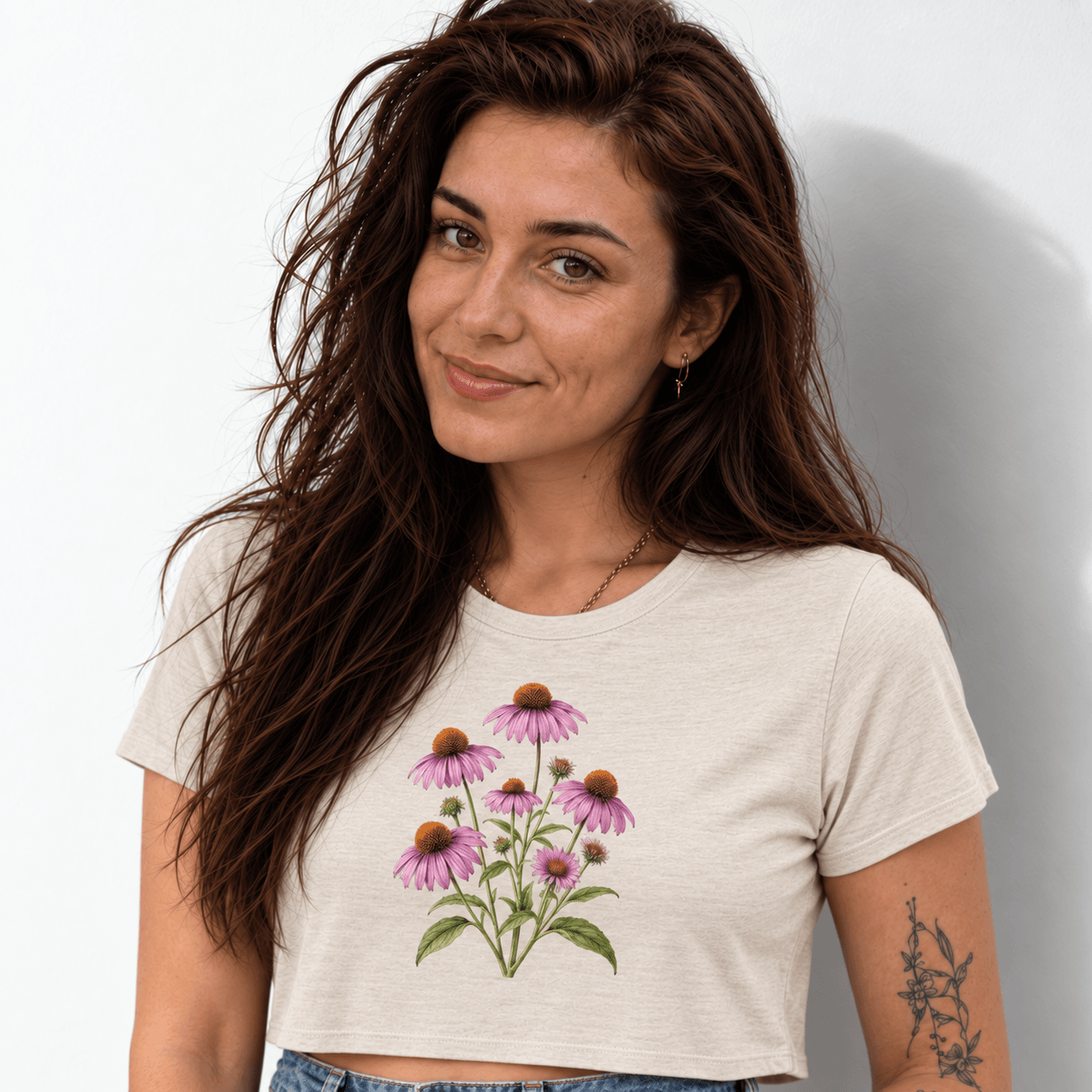 A woman wears a cream cropped tee with a purple coneflower print against a light background. AI-generated promotional image.